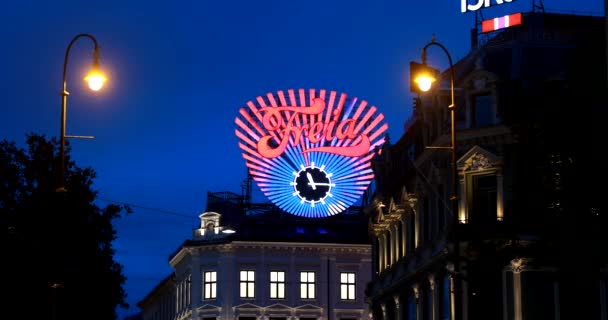 Oslo, Noruega - 24 de junho de 2019: Close Up The Freia Sign In Night. Sinal comercial antigo para o chocolate norueguês Freia. Doces de chocolate noruegueses empresa de fabricação de relógios Freia na Praça Egertorget. 4K — Vídeo de Stock