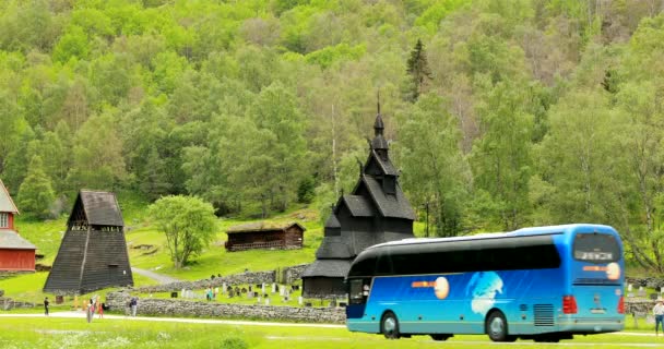 Borgund, Noorwegen - 14 juni 2019: Bus gaat op weg in de buurt van beroemde Noorse oriëntatiepunt Stavkirke Een oude houten drievoudige Nave-staafkerk Op zomerdag Rechtenvrije Stockvideo