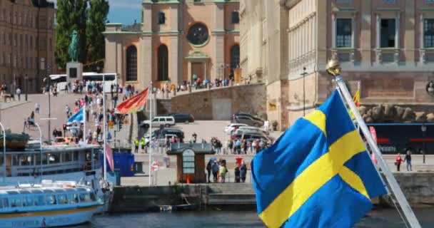 Estocolmo, Suécia - 28 de junho de 2019: Acenando com a bandeira sueca na Stockholm Street. 4K. Gamla Stan é Estocolmo Cidade Velha — Vídeo de Stock