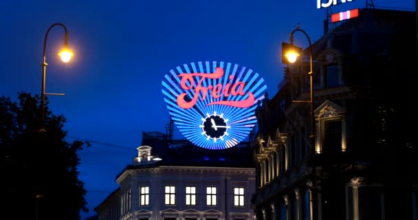 Oslo, Norsko - 24. června 2019: Zavřít Freia Přihlásit se v noci. Stará obchodní značka pro Norskou čokoládovou Freiu. Norské čokoládové bonbóny vyrábějící společnost Freia hodiny na Egertorget náměstí. 4K — Stock video