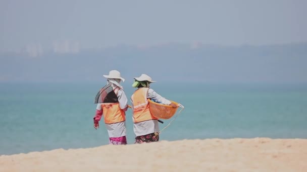 Arossim, Goa, India - 18 februari 2020: Twee vrouwen halen vuilnis op op het strand op zonnige dag op. Vrouw met vuilnismand. slow mo, slow motion. — Stockvideo