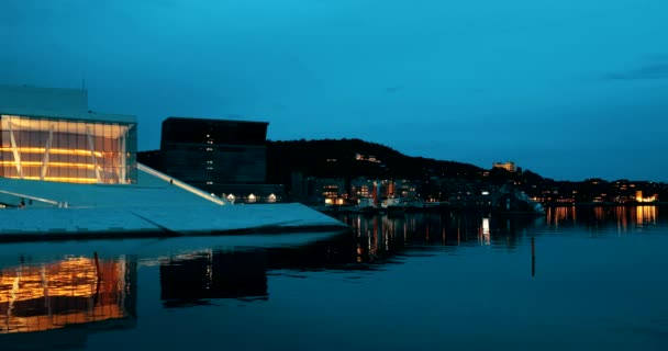 Oslo, Norvège - 25 juin 2019 : Vue en soirée de l'Opéra national et du ballet norvégiens illuminés parmi les bâtiments contemporains de grande hauteur — Video