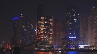 Dubai Marina Limanı, BAE, Birleşik Arap Emirlikleri - 19 Mayıs 2021: Akıllı telefondan Dubai Marina 'nın gece fotoğraflarını çeken kadın. Dubai Marina 'daki yüksek binaların gece görüşü. Pan