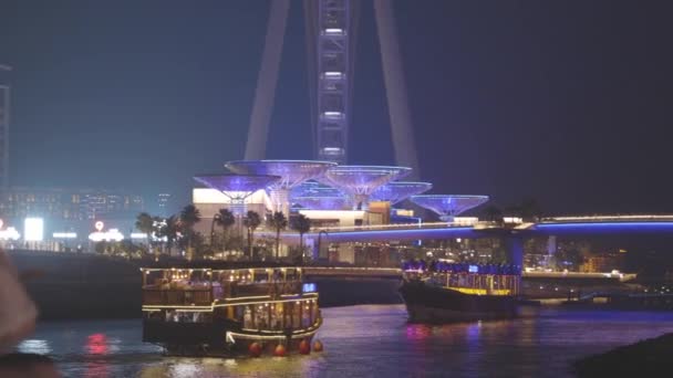 阿拉伯联合酋长国迪拜马里纳港。观光船、观光船在迪拜码头航行迪拜艾因附近的夜行是世界上最大的观察轮位于蓝水岛上。 免版税图库视频片段
