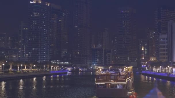 Порт Дубай Марина, Объединенные Арабские Эмираты - 19 мая 2021 года: лодка, прогулочный катер на Dubai Marina. Ночная прогулка возле Эйн-Дубая - самое большое колесо обозрения в мире, расположенное на Лицензионные Стоковые Видеоролики