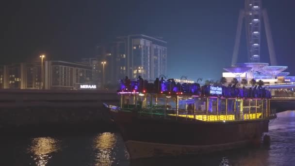 Порт Дубай Марина, Объединенные Арабские Эмираты - 19 мая 2021 года: лодка, прогулочный катер на Dubai Marina. Ночная прогулка возле Эйн-Дубая - самое большое колесо обозрения в мире, расположенное на Стоковое Видео