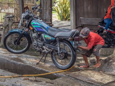 Jakarta, Endonezya - 20 Şubat 2018: Yerel adam Jakarta caddesinde motosikleti yıkıyor.