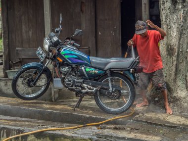 Jakarta, Endonezya - 20 Şubat 2018: Yerel adam Jakarta caddesinde motosikleti yıkıyor.