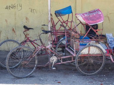 Wamena, Indonesia - January 23, 2015: A rickshaw driver. Young, dark skin boy waiting for a client on the street of Wamena