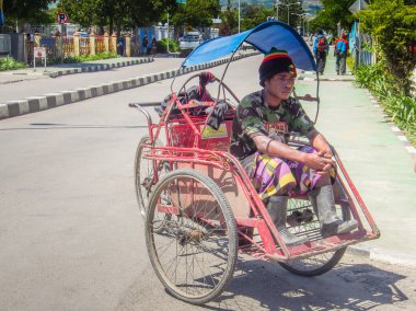 Wamena, Endonezya - 23 Ocak 2015: bir triportör şoförü. Genç, esmer tenli çocuk Wamena caddesinde müşteri bekliyor.