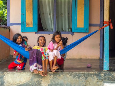 Ambon, Endonezya - 11 Şubat 2018: Endonezyalı bir grup genç kız, renkli giysiler içinde, Maluku, Maluki 'deki küçük bir köyde hamak üzerinde oturuyorlar.