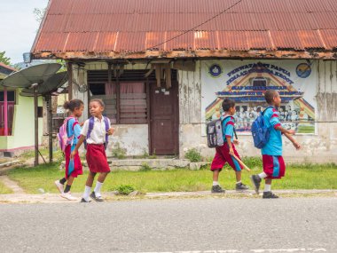 Kaimana, Indonesia - January 31, 2018: A group of Indonesian, children in blue and red uniform walking on the street in the small village on the West Papua