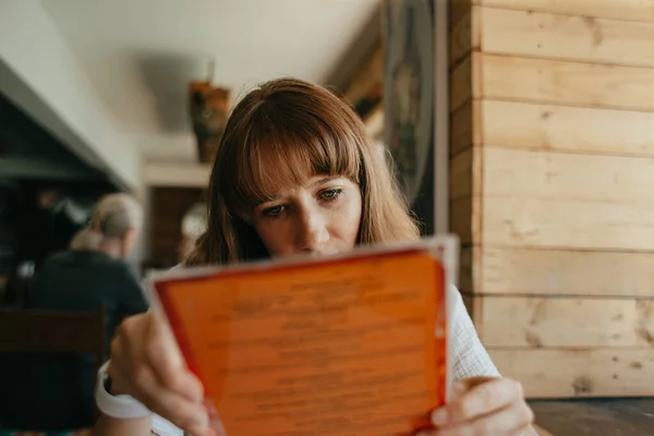 Young woman at a restaurant table with food menu