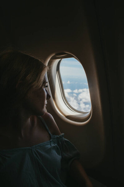 Young Blonde Woman Looking Out Airplane Window While Travelling Stock Photo