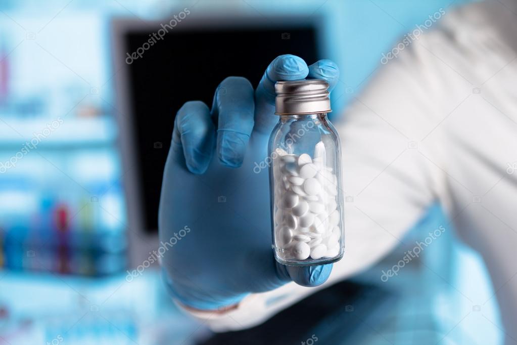 Hand of a pharmacist giving a bottle of pills