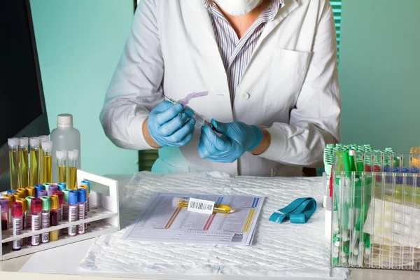 Trabalhador de laboratório manipula um tubo de sangue — Fotografia de Stock