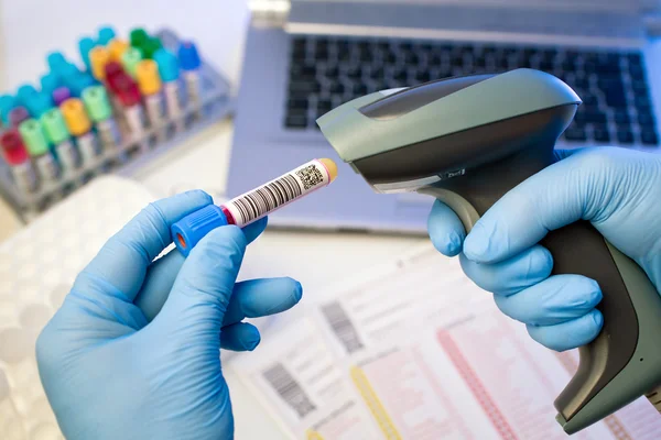 Hands scanning barcodes for tracking of blood sample — Stock Photo, Image