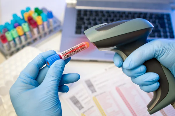 Mãos, digitalizando um rótulo de código de barras tubo para rastrear a amostra de sangue — Fotografia de Stock