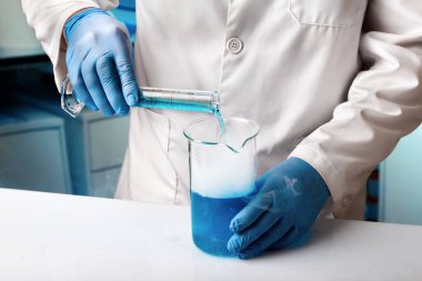 Sıvılarla yapılan deneylerin geliştirilmesi için araştırma laboratuvarında çalışan bir araştırmacı. Kimya laboratuvarında sıvıları karıştırmak için tüplerle çalışan bir bilim adamı.