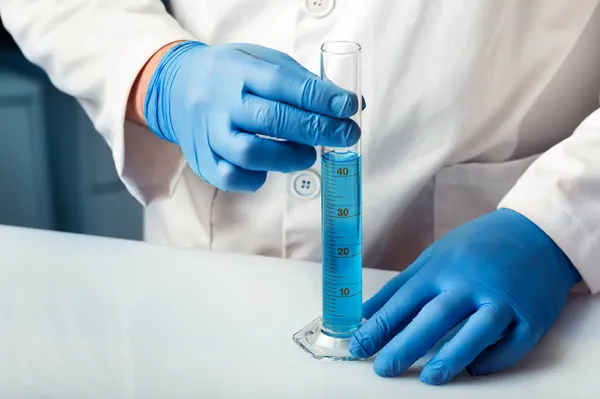 研究室内の液体を分析するための試験管を保持する研究者 研究者白色試験管の研究室内の流体を分析する卒業シリンダー — ストック写真