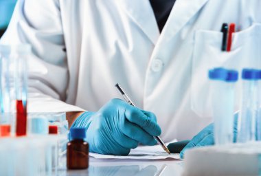 Bilim adamı laboratuardaki çalışmalar hakkında notlar alıyor. Doktor muayenehanesindeki bir hasta için reçete yazdı.
