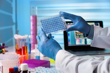 Scientist working in laboratory with samples in micro plate. Researcher in lab holding a 96 well plate with biological samples for analysis