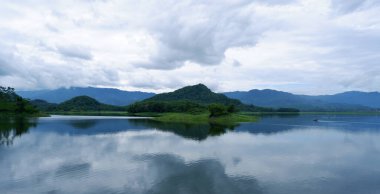 Güzel Malahayu Gölü 'nün ortasında bir ada. Göl manzarası mavi ve yeşildir. Birkaç balıkçı teknesi var ve hava bulutlu..