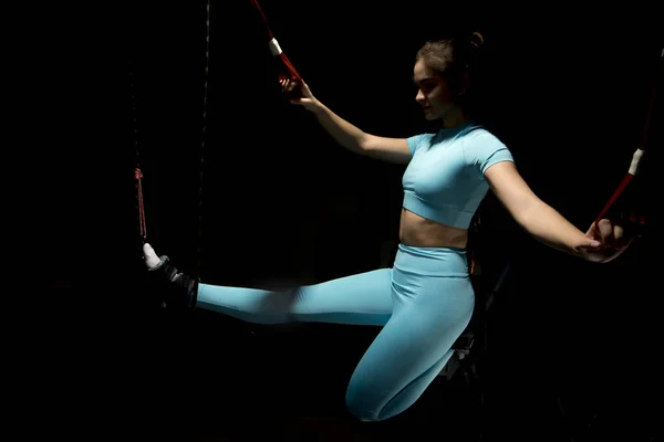 Pelatihan Alfagravity, olahraga baru. Wanita atletik muda dalam pakaian olahraga melatih kaki dengan tali kebugaran Alfagravity di gym. Foto berkualitas tinggi — Stok Foto