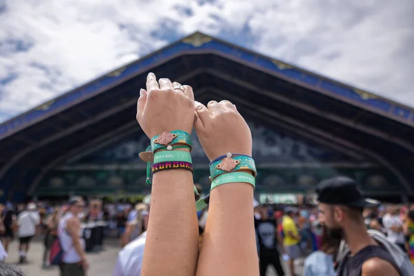 Two friends show their festival wrist bands as they prepare to enter Tomorrowland 2022.