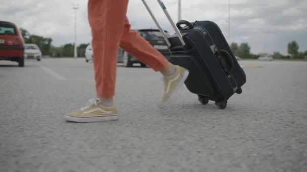 Mujer con maleta caminando en un estacionamiento — Vídeo de stock