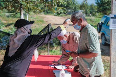 Muadzam Şah, Malezya - 6 Ekim 2021: Asyalı bir adam Durian 'da kızılötesi termometreyle ve Muadzam Şah' ta ananas bahçelerinde ateşini ölçüyor