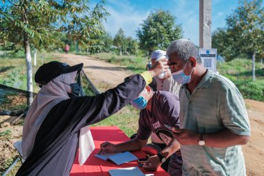Muadzam Şah, Malezya - 6 Ekim 2021: Asyalı bir adam Durian 'da kızılötesi termometreyle ve Muadzam Şah' ta ananas bahçelerinde ateşini ölçüyor