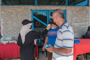 Muadzam Şah, Malezya - 6 Ekim 2021: Asyalı bir adam Durian 'da kızılötesi termometreyle ve Muadzam Şah' ta ananas bahçelerinde ateşini ölçüyor