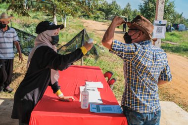 Muadzam Şah, Malezya - 6 Ekim 2021: Asyalı bir adam Durian 'da kızılötesi termometreyle ve Muadzam Şah' ta ananas bahçelerinde ateşini ölçüyor
