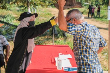Muadzam Şah, Malezya - 6 Ekim 2021: Asyalı bir adam Durian 'da kızılötesi termometreyle ve Muadzam Şah' ta ananas bahçelerinde ateşini ölçüyor