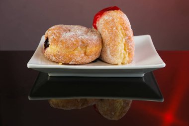 Reçelli Bomboloni çörekleri ve beyaz tabakta krema şekeri.