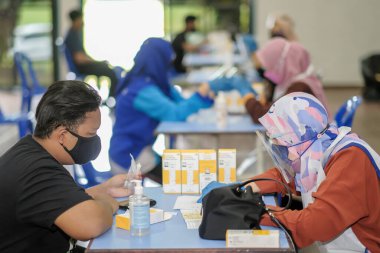 Muadzam Şah, Malezya - 31 Ekim 2021: Öğrenciler salonda tükürük örneğiyle Covid-19 hızlı testi yapıyorlar.