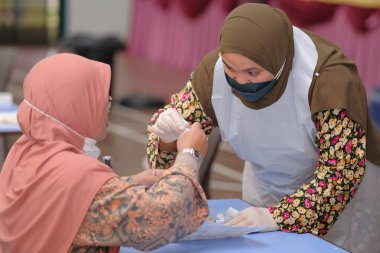 Muadzam Şah, Malezya - 25 Ocak 2022: Öğretmen salonda tükürük örneğiyle Covid-19 hızlı testi yaptı.