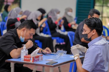 Muadzam Şah, Malezya - 25 Ocak 2022: Öğretmen salonda tükürük örneğiyle Covid-19 hızlı testi yaptı.