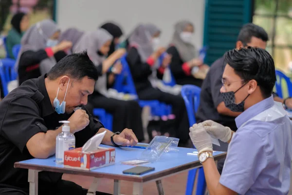 Muadzam Şah, Malezya - 25 Ocak 2022: Öğretmen salonda tükürük örneğiyle Covid-19 hızlı testi yaptı.