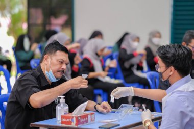 Muadzam Şah, Malezya - 25 Ocak 2022: Öğretmen salonda tükürük örneğiyle Covid-19 hızlı testi yaptı.