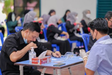 Muadzam Şah, Malezya - 25 Ocak 2022: Öğretmen salonda tükürük örneğiyle Covid-19 hızlı testi yaptı.