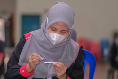 Muadzam Şah, Malezya - 25 Ocak 2022: Öğretmen salonda tükürük örneğiyle Covid-19 hızlı testi yaptı.