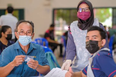 Muadzam Şah, Malezya - 25 Ocak 2022: Öğretmen salonda tükürük örneğiyle Covid-19 hızlı testi yaptı.