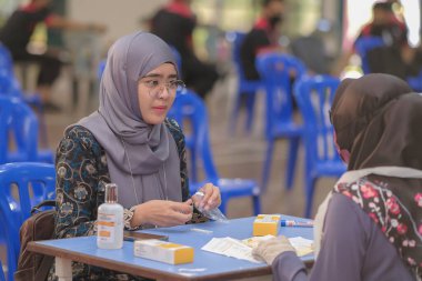 Muadzam Şah, Malezya - 25 Ocak 2022: Öğretmen salonda tükürük örneğiyle Covid-19 hızlı testi yaptı.