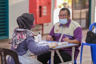Muadzam Şah, Malezya - 25 Ocak 2022: Öğretmen salonda tükürük örneğiyle Covid-19 hızlı testi yaptı.