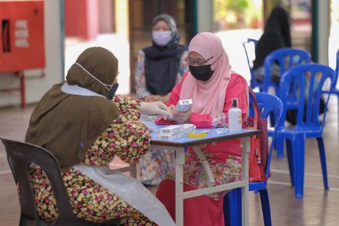 Muadzam Şah, Malezya - 25 Ocak 2022: Öğretmen salonda tükürük örneğiyle Covid-19 hızlı testi yaptı.