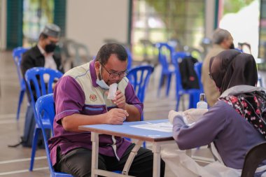 Muadzam Şah, Malezya - 25 Ocak 2022: Öğretmen salonda tükürük örneğiyle Covid-19 hızlı testi yaptı.