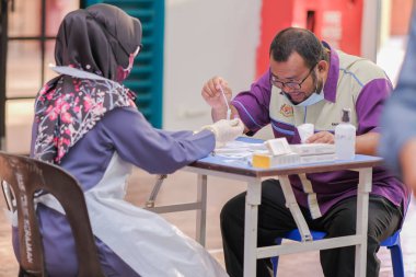 Muadzam Şah, Malezya - 25 Ocak 2022: Öğretmen salonda tükürük örneğiyle Covid-19 hızlı testi yaptı.