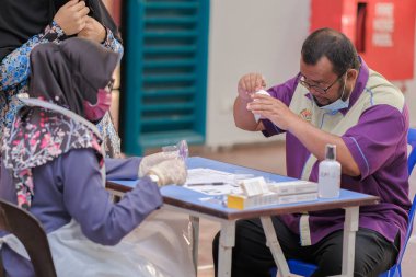 Muadzam Şah, Malezya - 25 Ocak 2022: Öğretmen salonda tükürük örneğiyle Covid-19 hızlı testi yaptı.